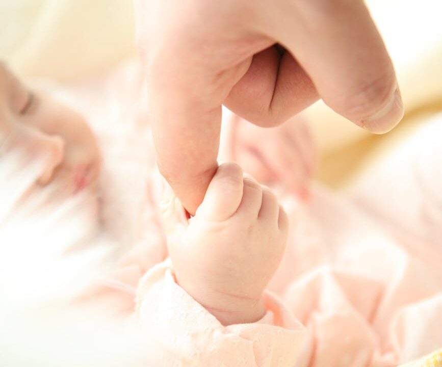 baby holding person s index finger